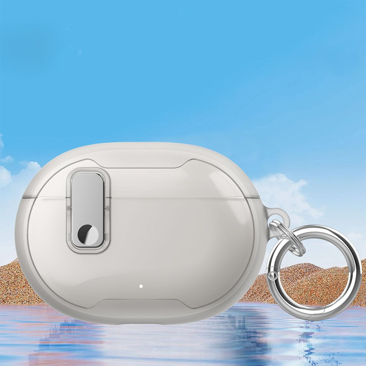 A white, oval-shaped earbud case with a silver ring. The background shows a blue sky over a sandy beach and water.