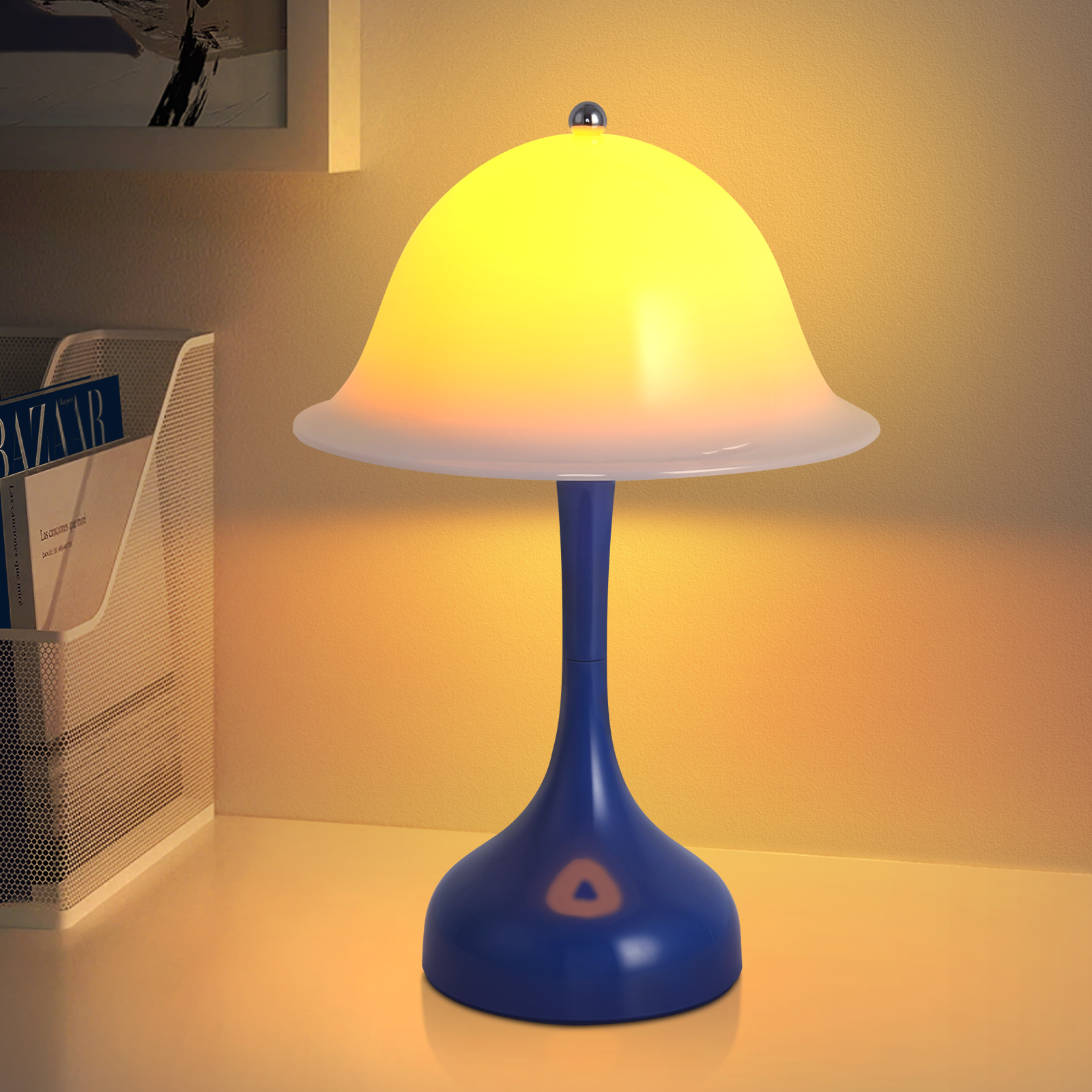 Una lampada blu con un paralume giallo brillante è su una scrivania. Un portariviste con riviste a sinistra.