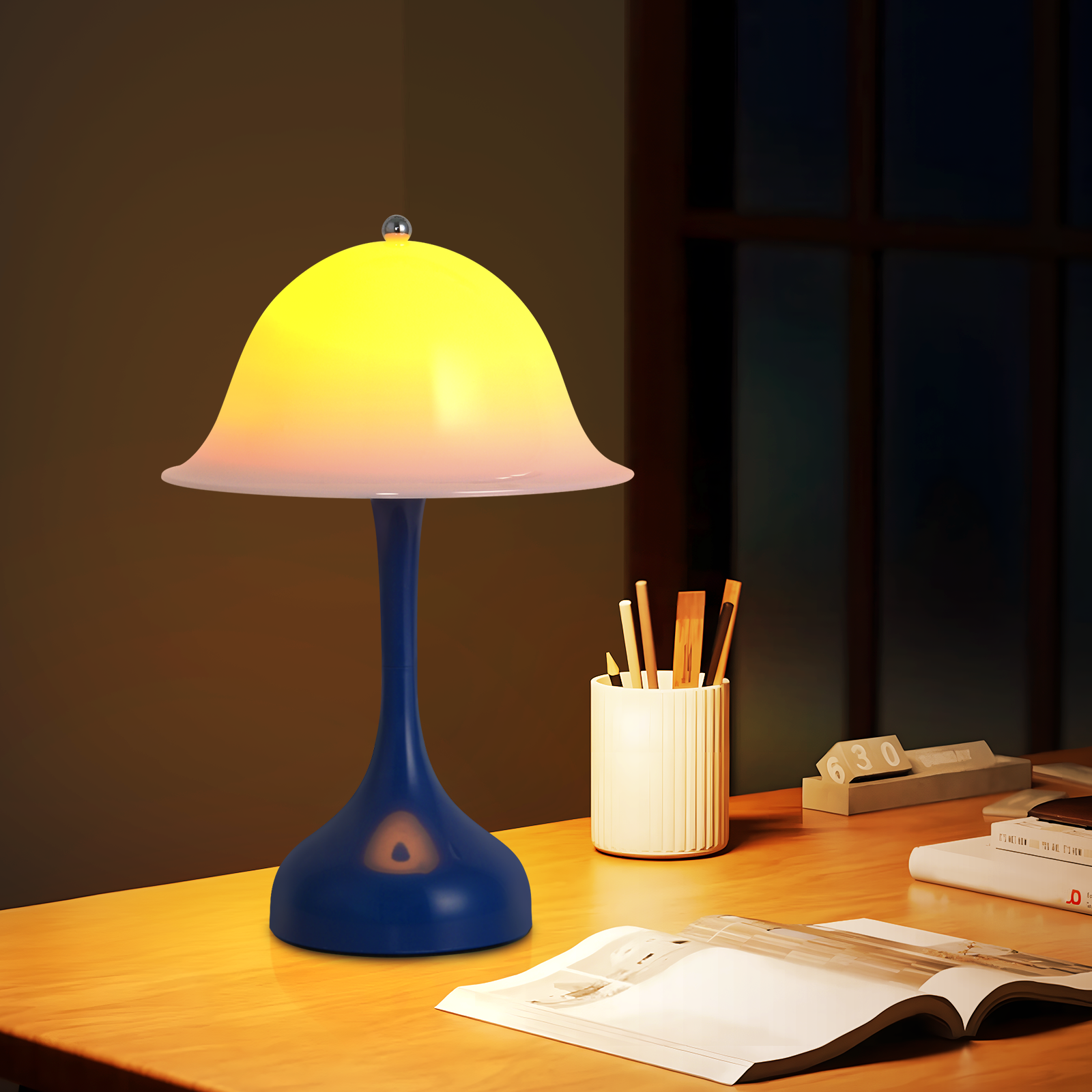 Una lampada blu con paralume giallo è su una scrivania di legno. Accanto ci sono penne, libri e un calendario.
