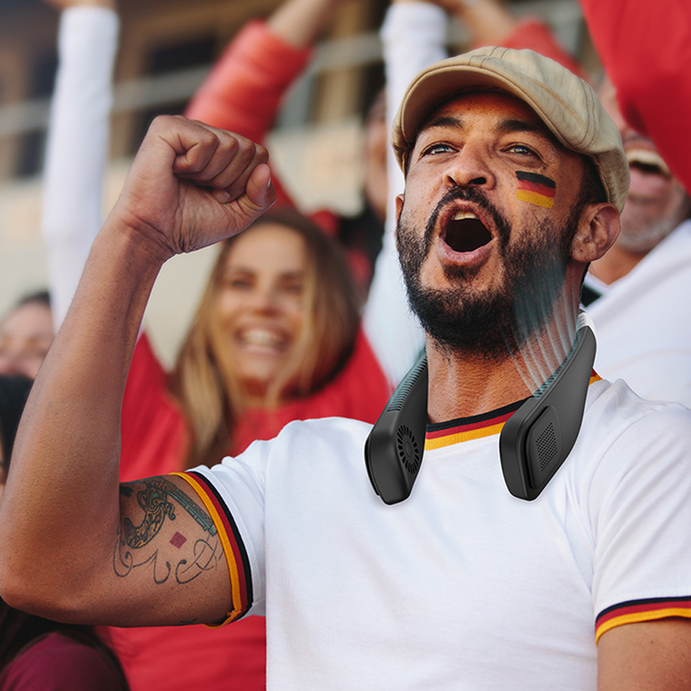 Ein Mann mit Gesichtsbemalung und Nackenventilator jubelt bei einem Spiel. Er trägt ein weißes Hemd mit schwarz-gelbem Besatz und eine Kappe.