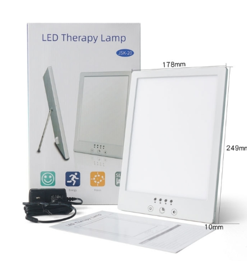 LED-Therapielampe mit Karton, Netzteil und Handbuch. Die Lampe ist weiß, hat einen hellen Bildschirm und die Box hat Symbole.