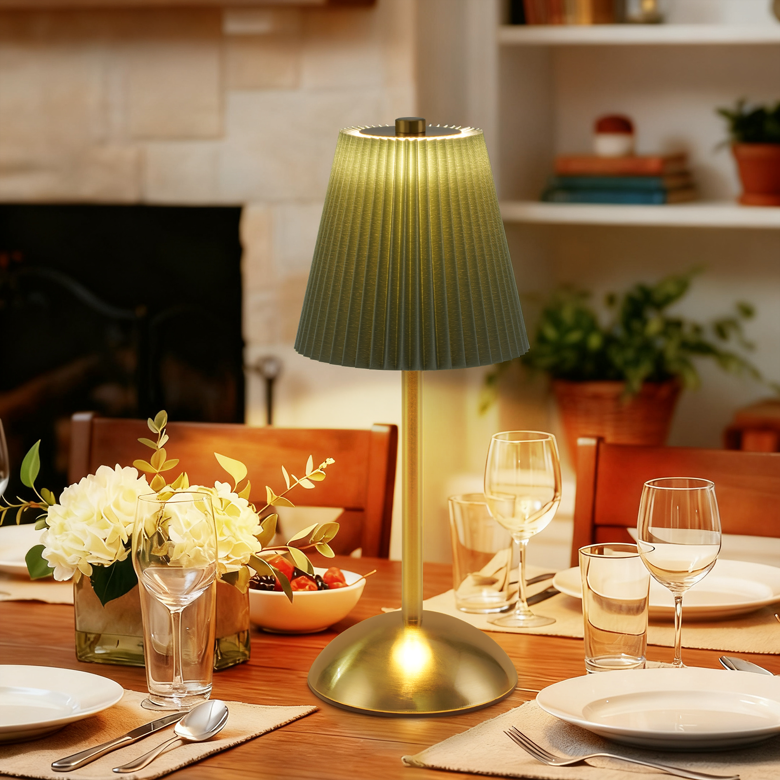 Tavola apparecchiata con lampada, fiori, bicchieri, piatti. Sullo sfondo camino e mensole.