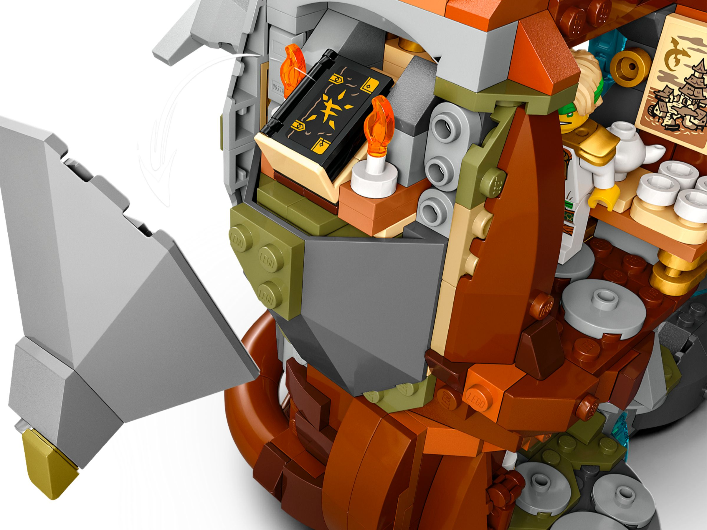 Lego-Set mit schwarzem Buch, orangefarbenen Flammen und Figur. Grauer Schild, braune und grüne Struktur. Weißer Hintergrund.