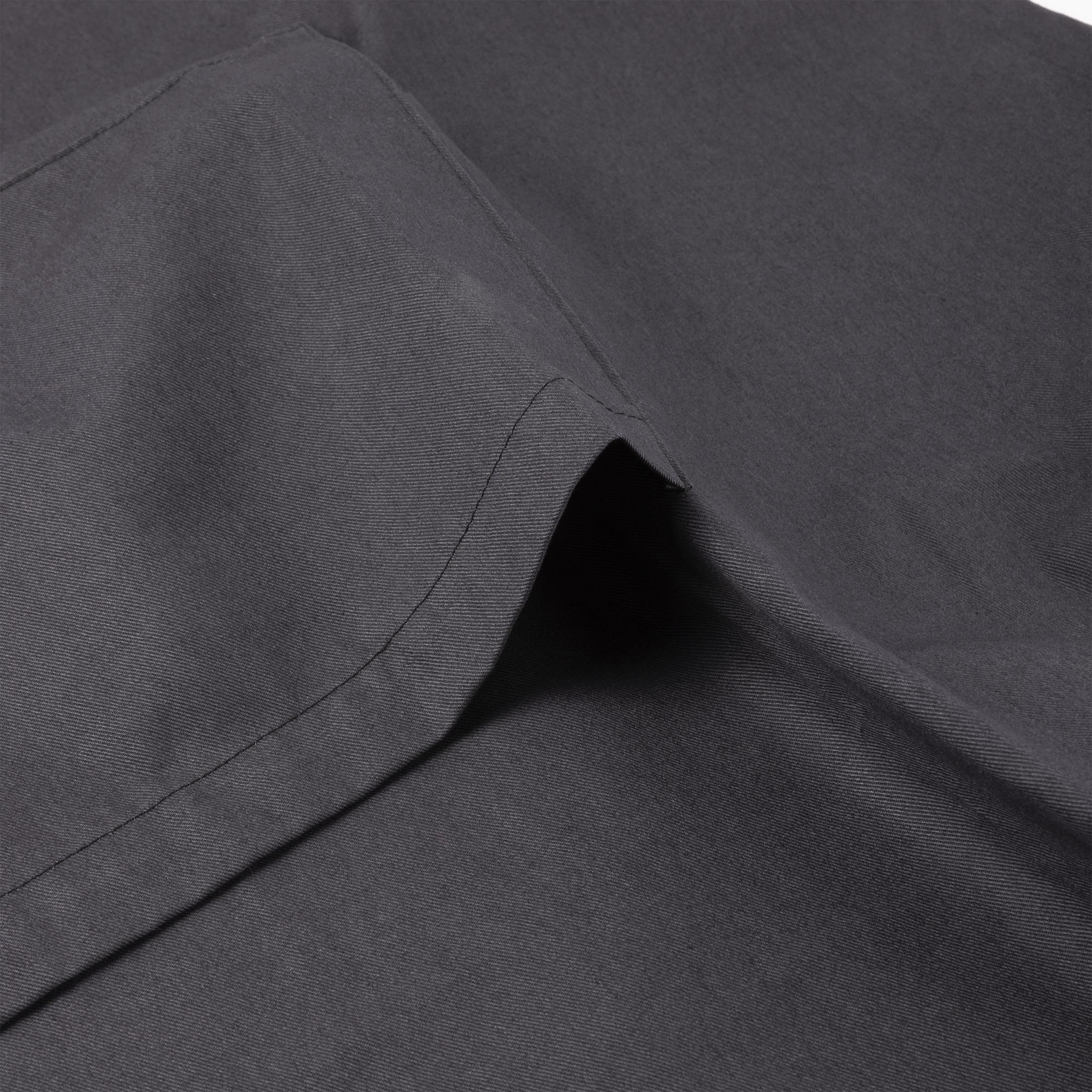 Primer plano de tela gris doblada. Las costuras y texturas visibles indican el material.