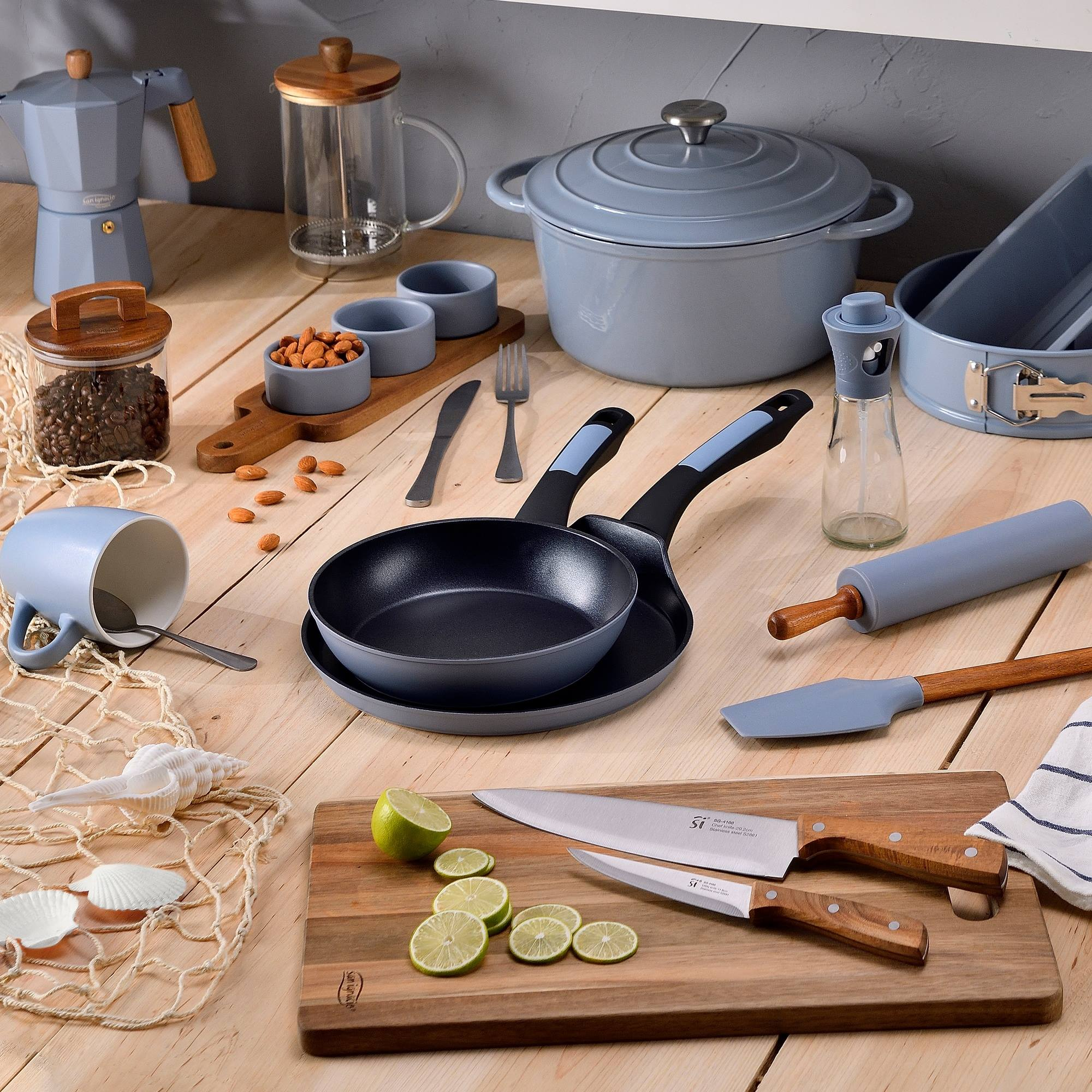 Montaje de cocina: utensilios de cocina, utensilios e ingredientes como limones y almendras, dispuestos sobre madera.