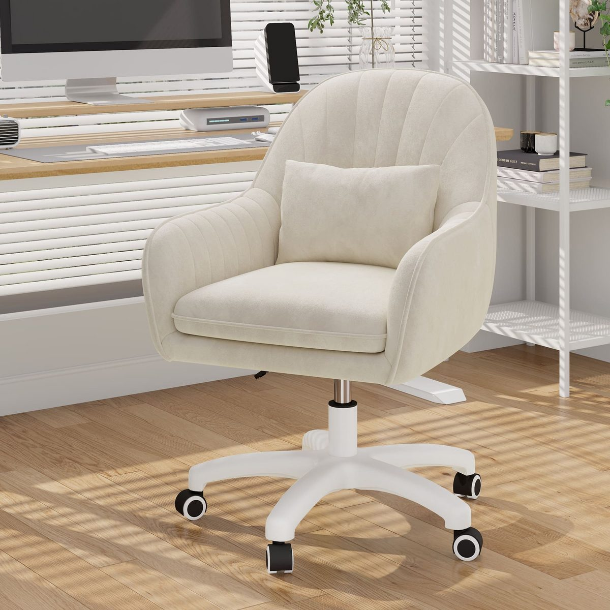 Silla de oficina color crema con almohada. Escritorio con ordenador y teléfono. Estanterías blancas con objetos. Suelo de madera con luz.