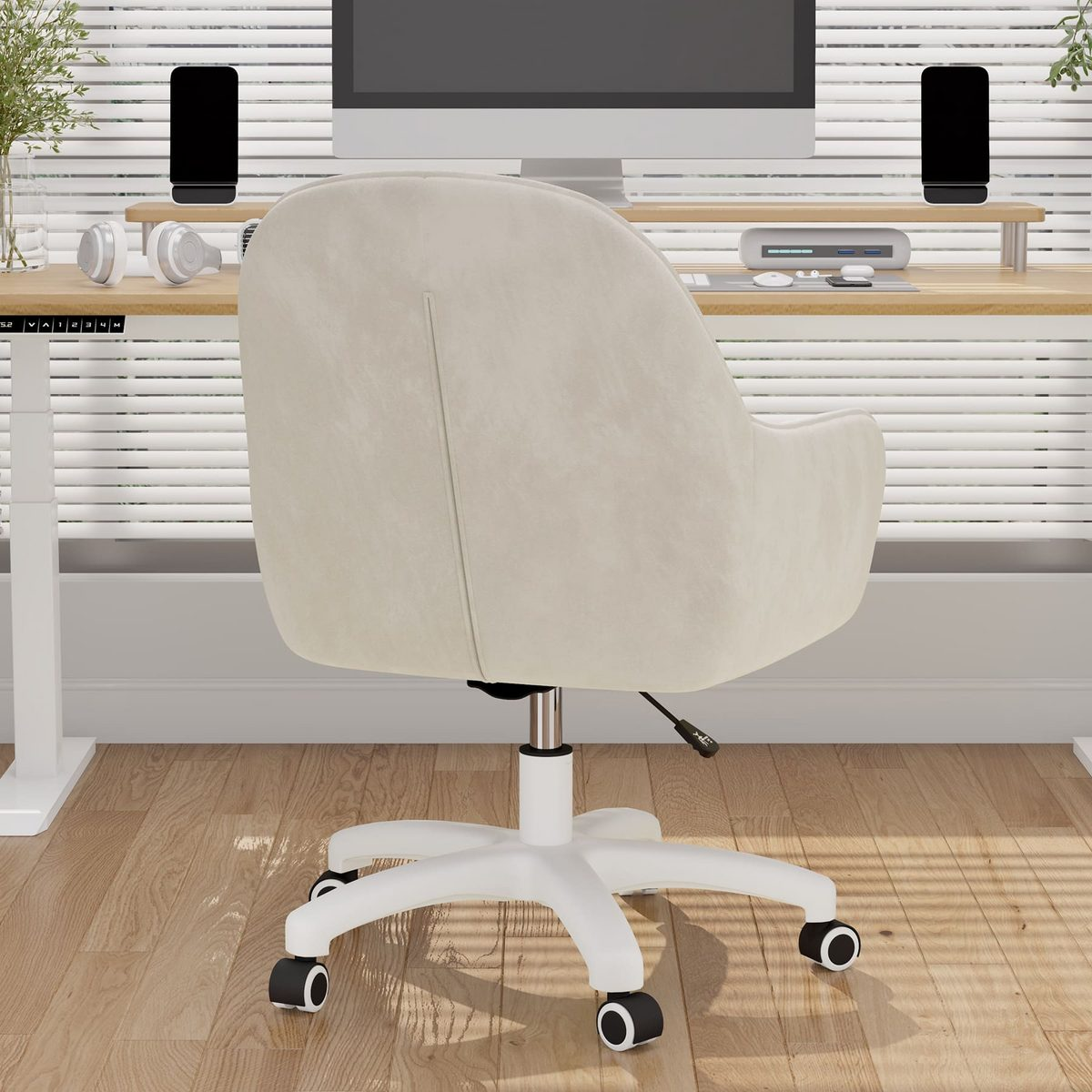 Una silla de oficina color crema mira al espectador. Un escritorio con un monitor, altavoces y accesorios está detrás de la silla.