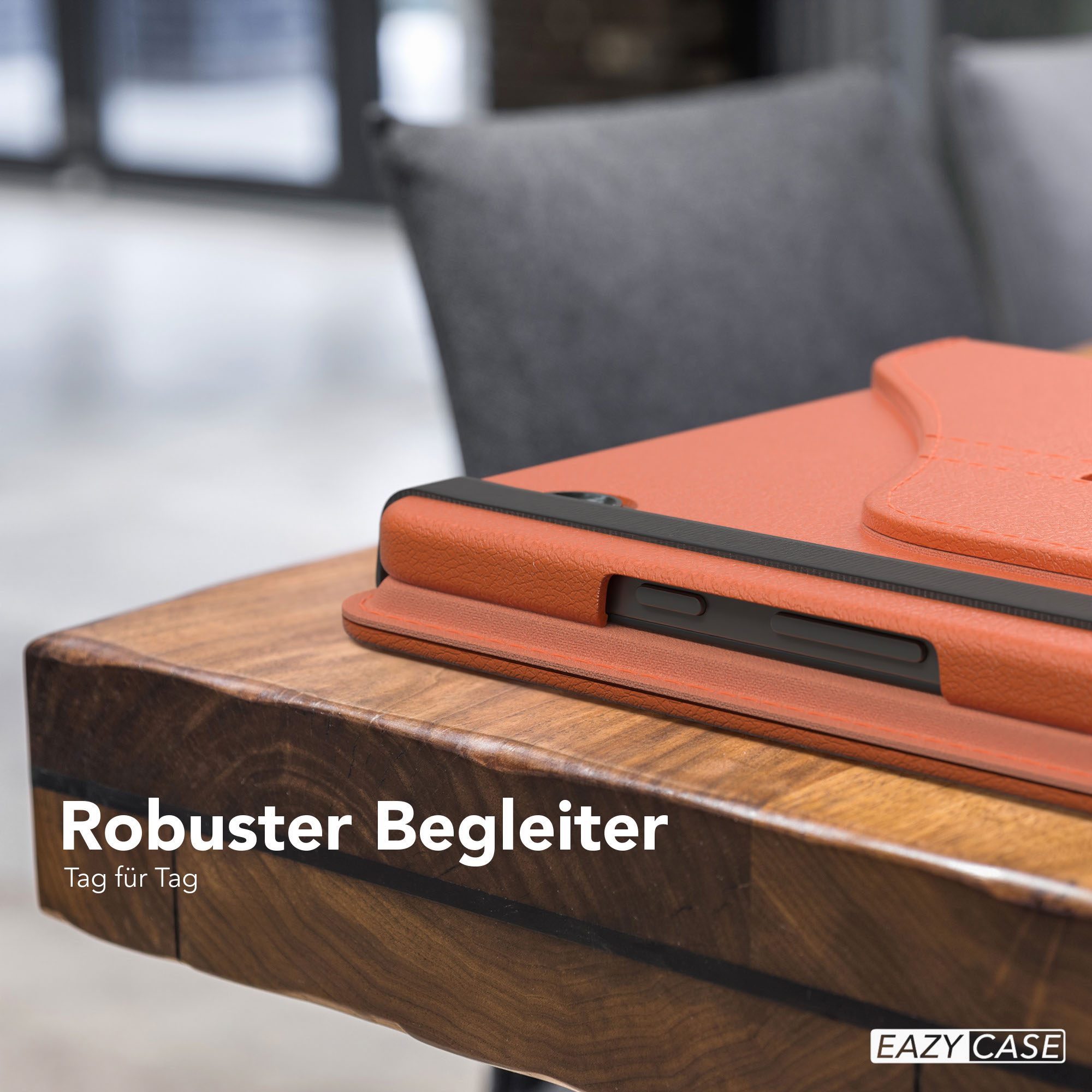 Eine orangefarbene Tablethülle auf einem Holztisch. Im Hintergrund sieht man einen Stuhl und ein verschwommenes Fenster.