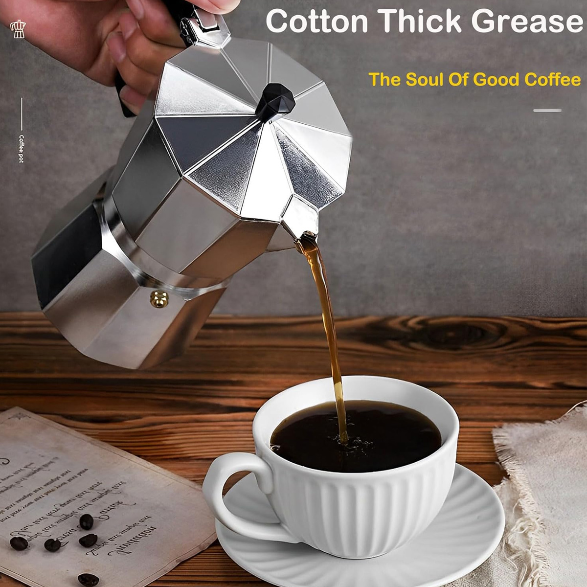Eine Metallkaffeekanne gießt Kaffee in eine weiße Tasse auf einer Untertasse. Kaffeebohnen und ein Papier liegen auf einer Holzoberfläche.
