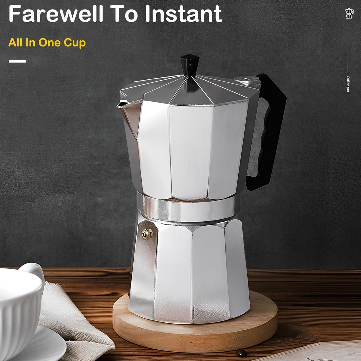 Eine silberne Espressokanne auf einem Holzuntersetzer. Eine weiße Tasse befindet sich im Vordergrund. Der Hintergrund ist eine dunkelgraue Oberfläche.