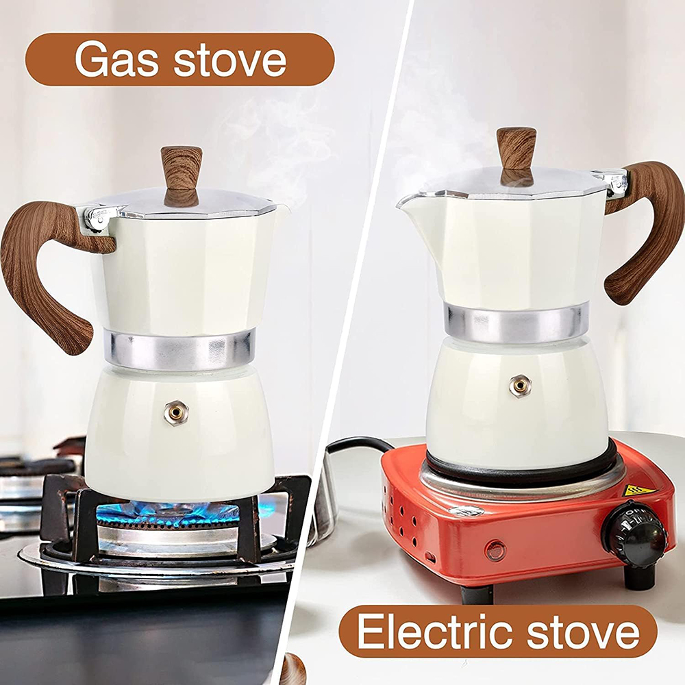 Zwei cremefarbene Kaffeemaschinen, eine auf einem Gasherd und die andere auf einem Elektroherd. Dampf steigt auf. Holzgriffe sind sichtbar.
