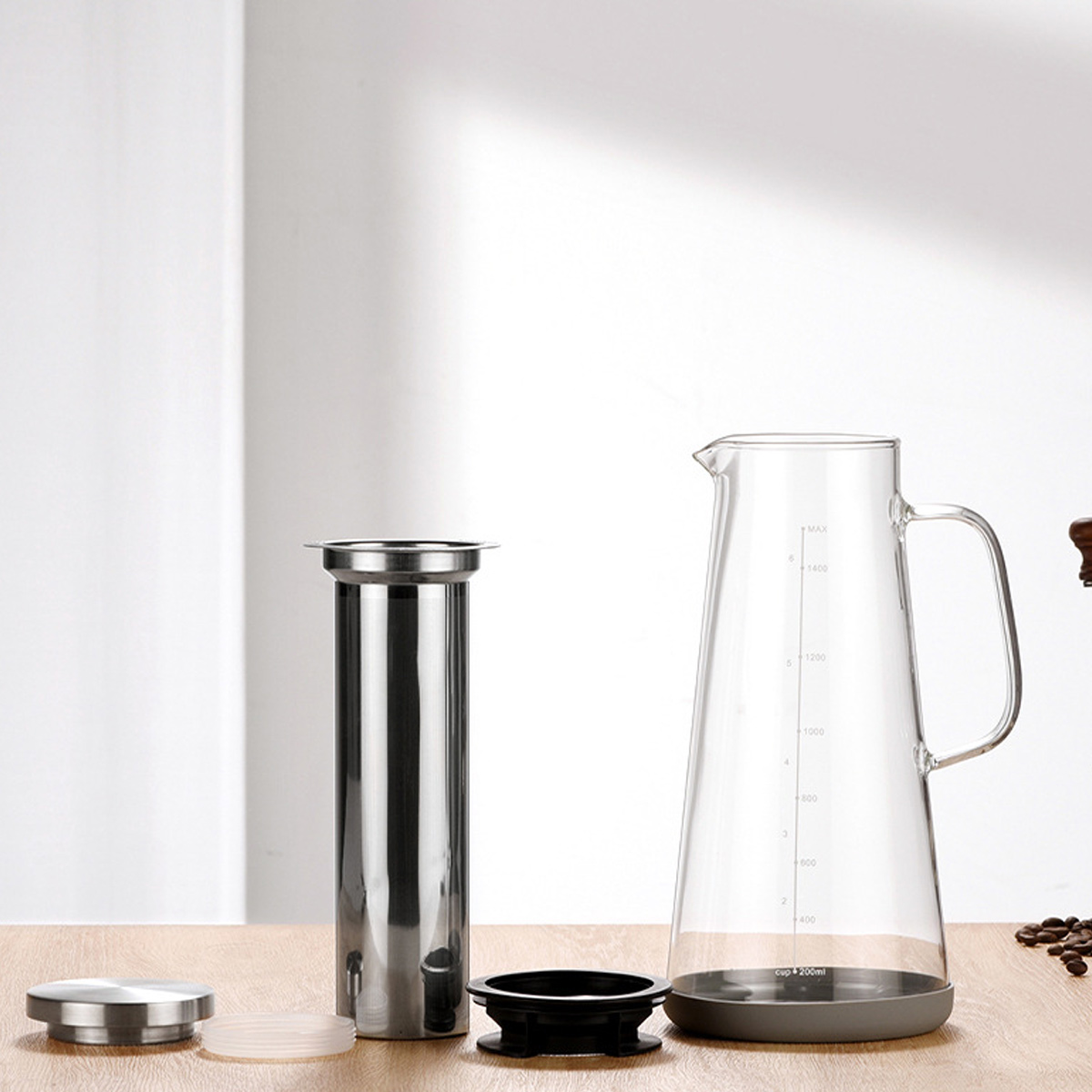 Ein Kaffeebereiter mit Glaskaraffe, Edelstahlfilter und schwarzem und silbernem Deckel steht auf einer Holzoberfläche.