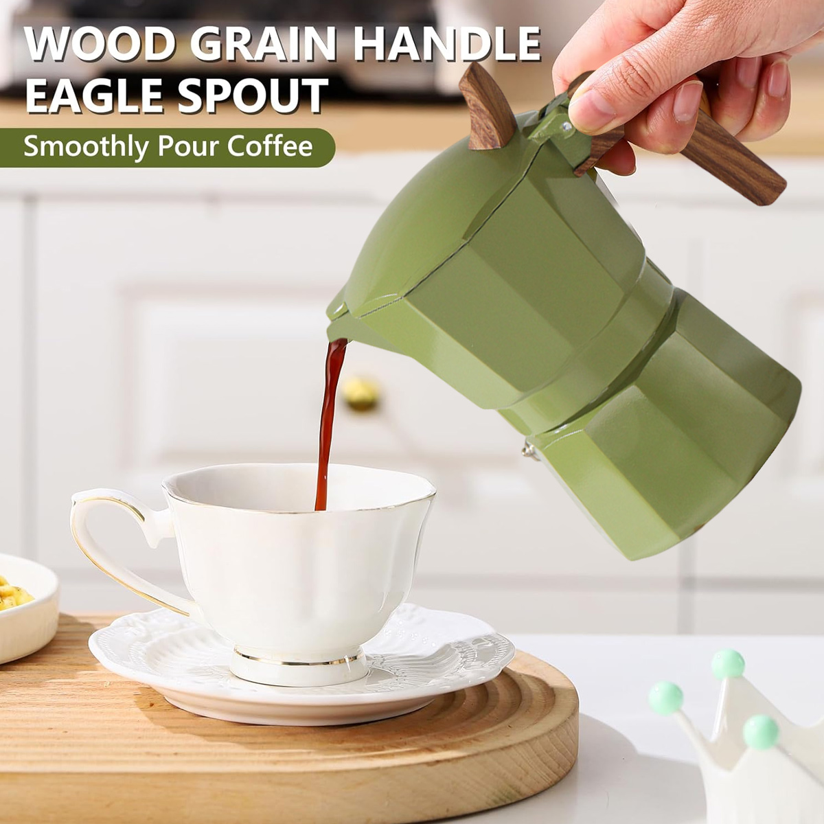 Ein grüner Kaffeezubereiter gießt Kaffee in eine weiße Tasse auf einer Untertasse. Der Griff ist holzmaseriert. Eine Hand hält den Kaffeezubereiter.