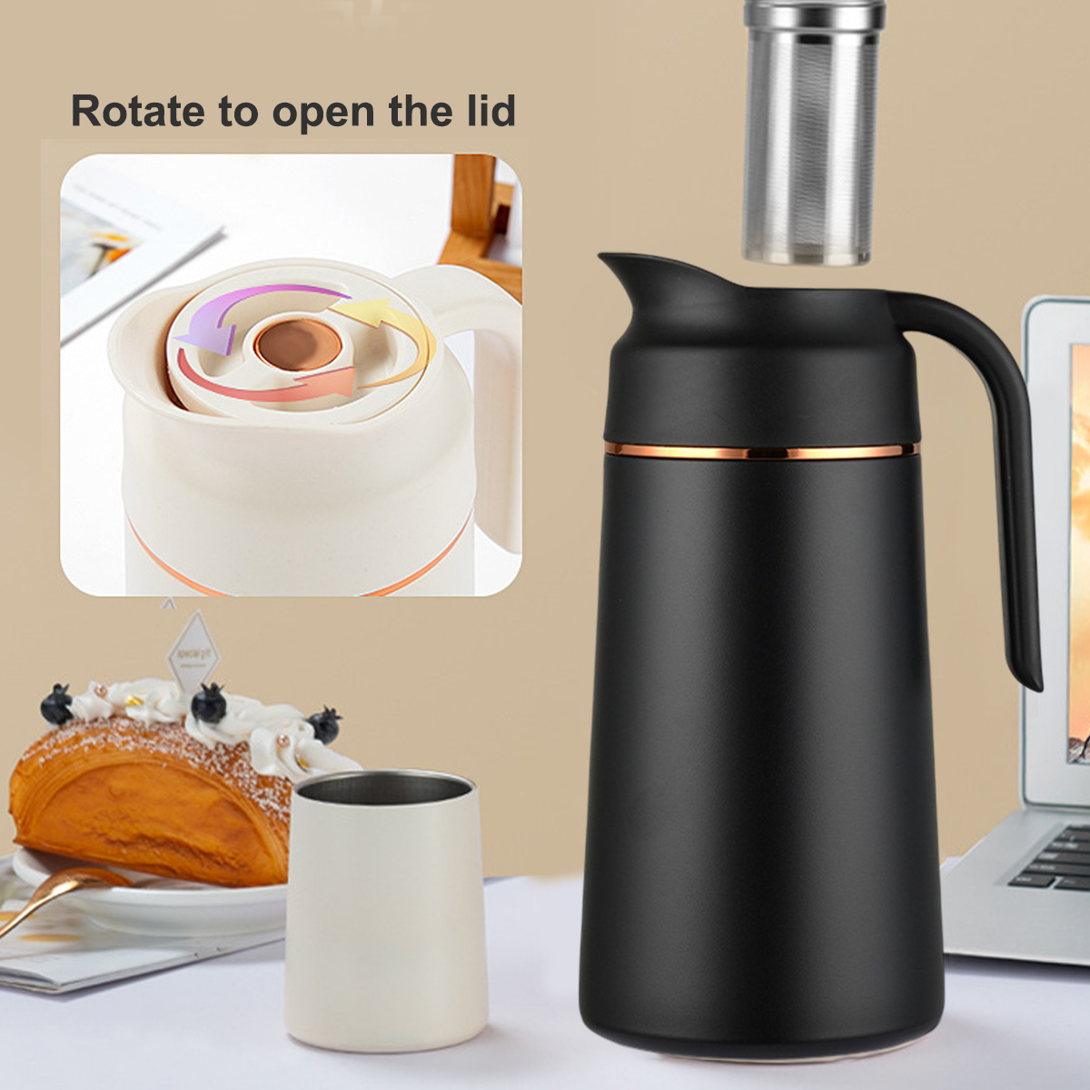Eine schwarze Thermoskanne mit Henkel und eine Tasse. Auf dem Tisch liegen auch ein Gebäck und ein Laptop. Der Deckel öffnet sich durch Drehen.
