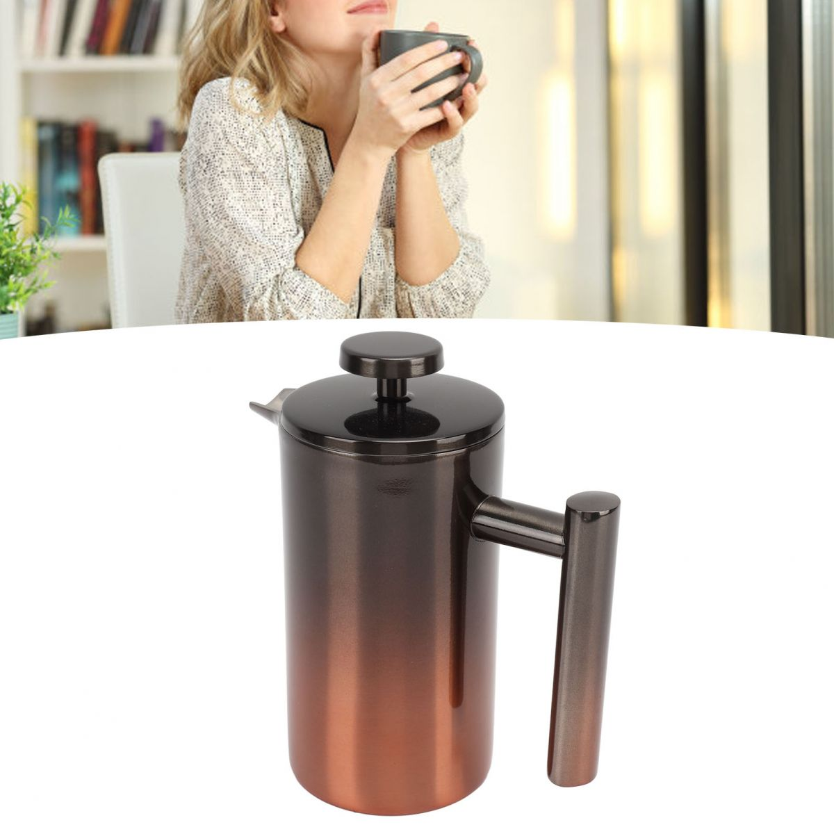 Eine Frau hält eine Tasse, im Vordergrund eine Kaffeepresse. Die Presse ist metallisch, hat einen Griff an der Seite und einen schwarzen Deckel.