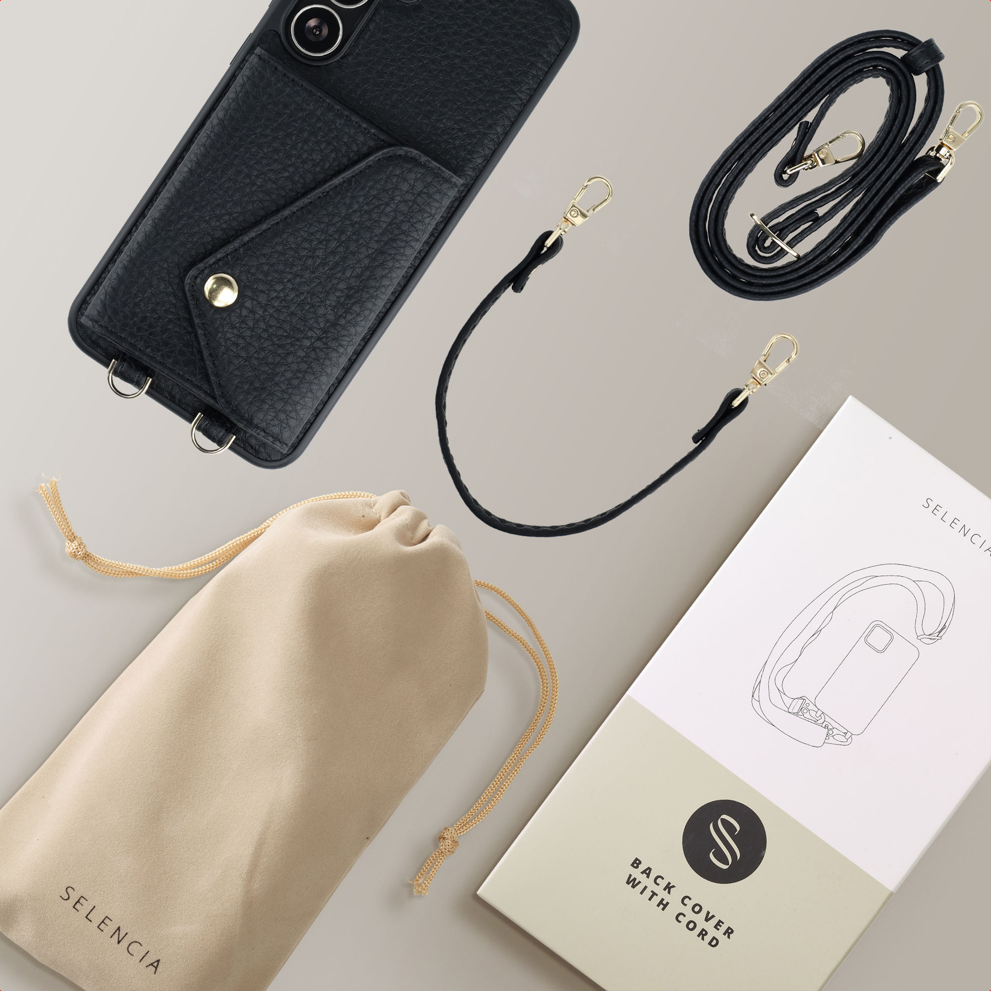 Zwarte telefoonhoes met riem, zakje, riem en doos. Gouden hardware. Beige achtergrond.