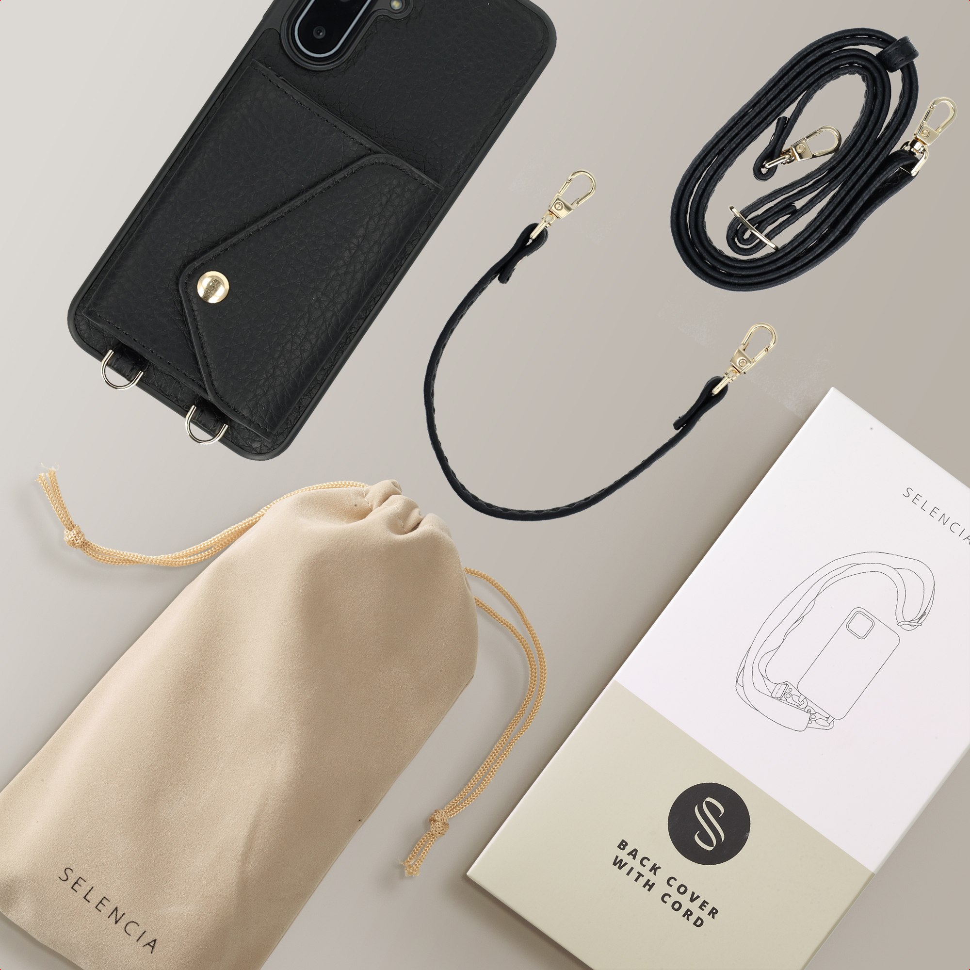 Zwarte telefoonhoes met een zak, zwarte riem met gouden sluitingen, beige zakje en een doos. Alles op een lichtgrijze ondergrond.