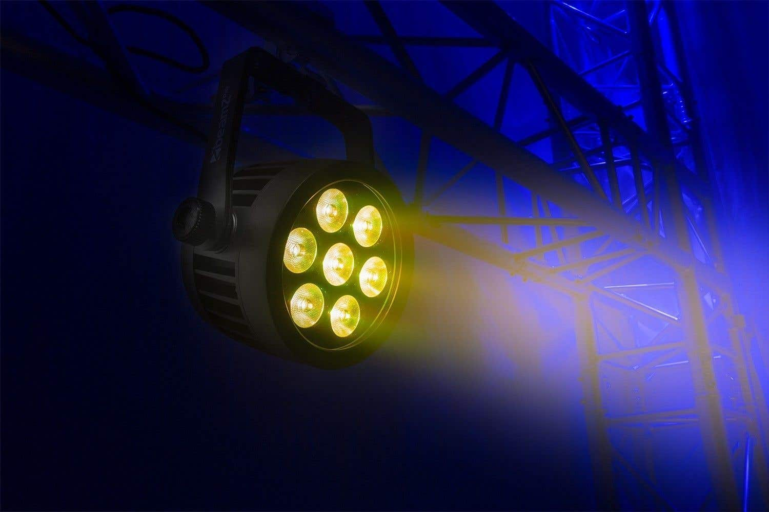 Una luz de escenario con siete LED amarillos brillantes, montada sobre una estructura metálica. El fondo es azul oscuro con algunas luces azules.