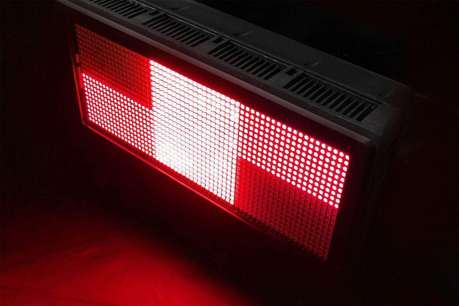Una luz LED rectangular que emite luz roja. La luz tiene un patrón de cuadrícula. El fondo es oscuro.