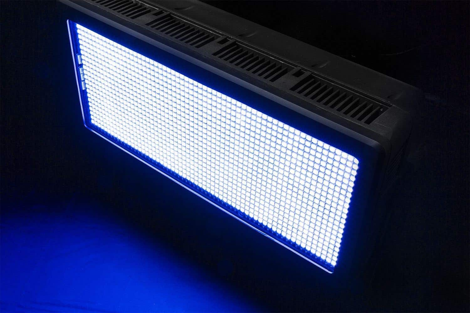 Una luz LED rectangular que emite una luz azul brillante. Está en un marco negro, inclinado contra un fondo oscuro.