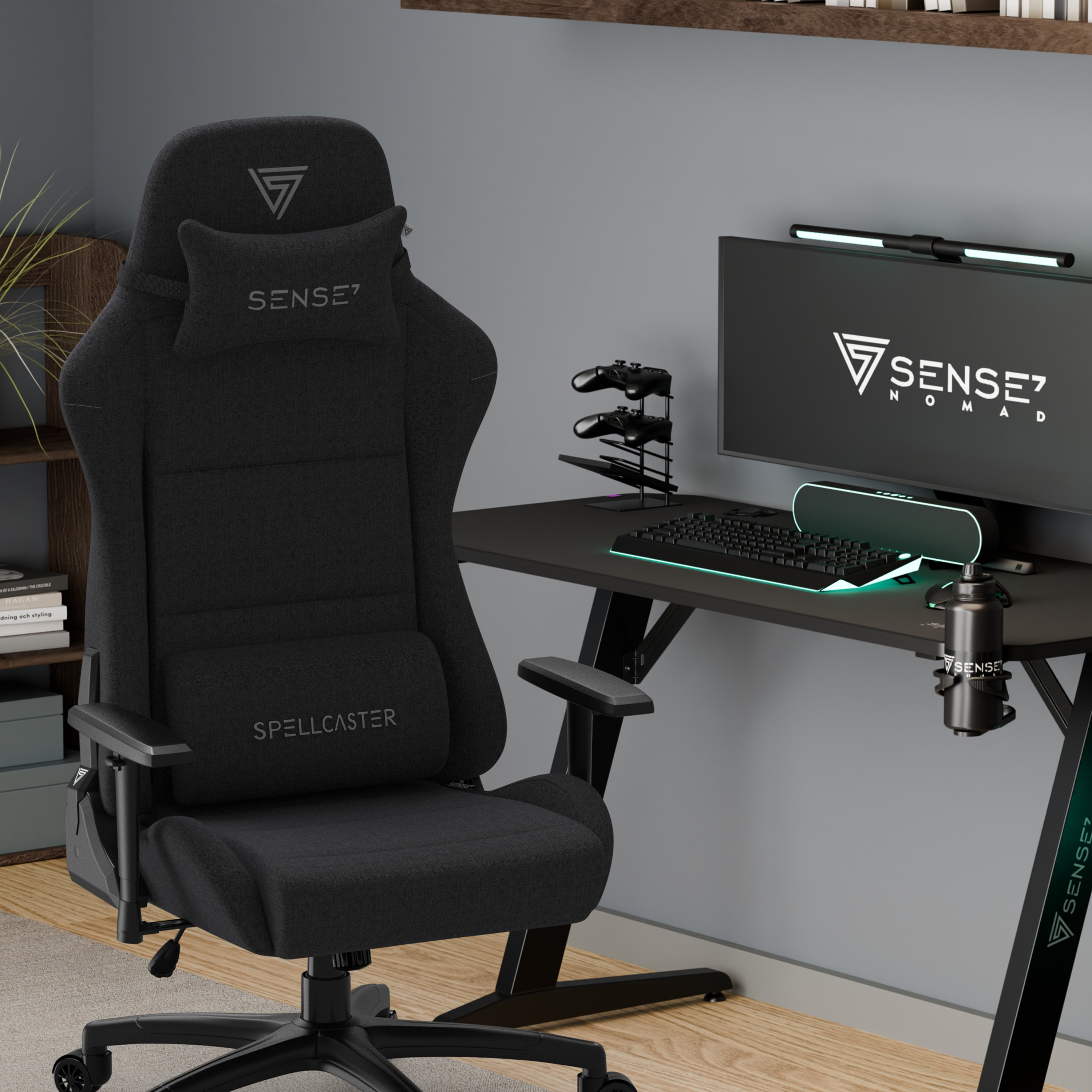 Ein schwarzer Gaming-Stuhl, ein Schreibtisch und ein Monitor befinden sich in einem Raum. Der Monitor zeigt das Logo von Sense7 Nomad.