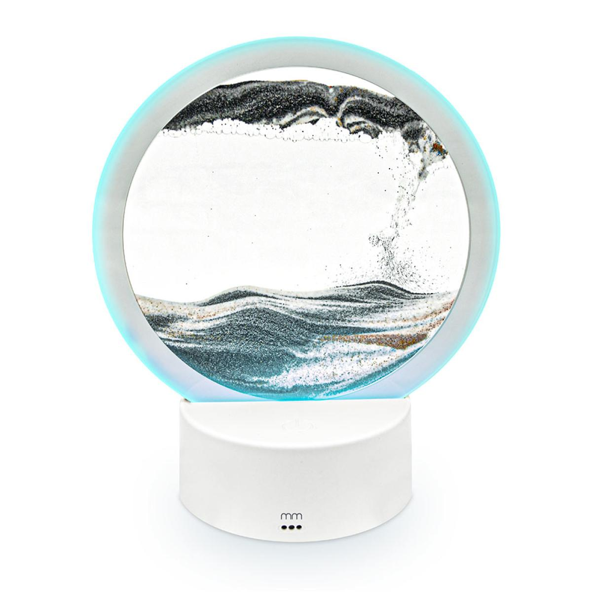 Een rond zandkunstwerk met een blauwe halo, op een witte voet. Zand creëert een golfpatroon. De voet heeft drie stippen.