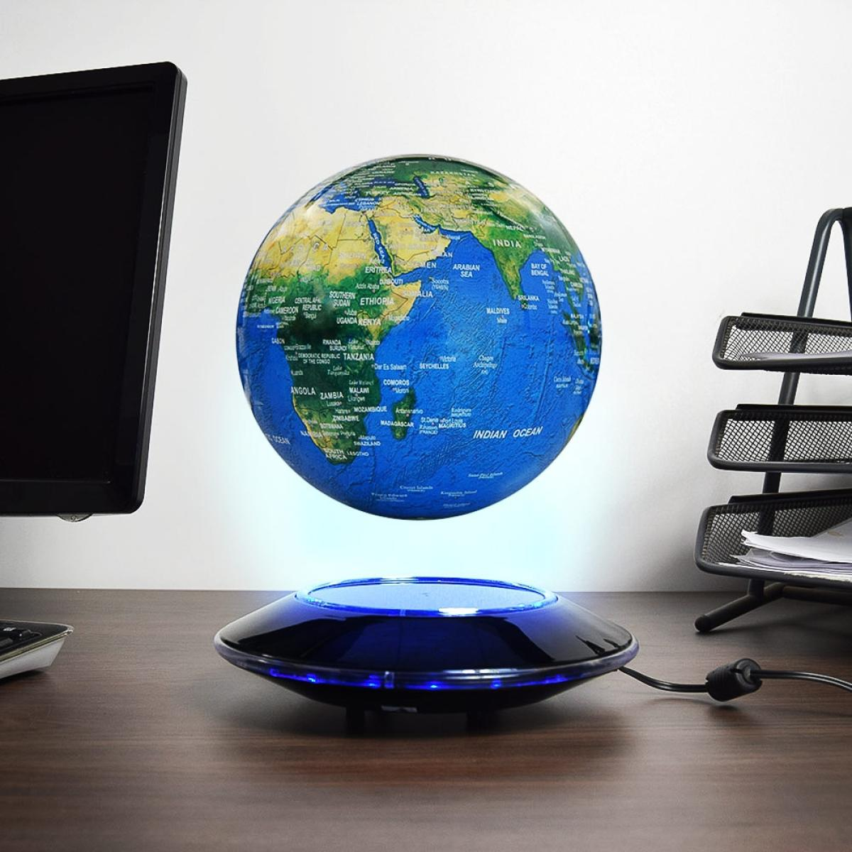 Een zwevende wereldbol boven een voet op een bureau, met een computermonitor en een papiermand op de achtergrond.