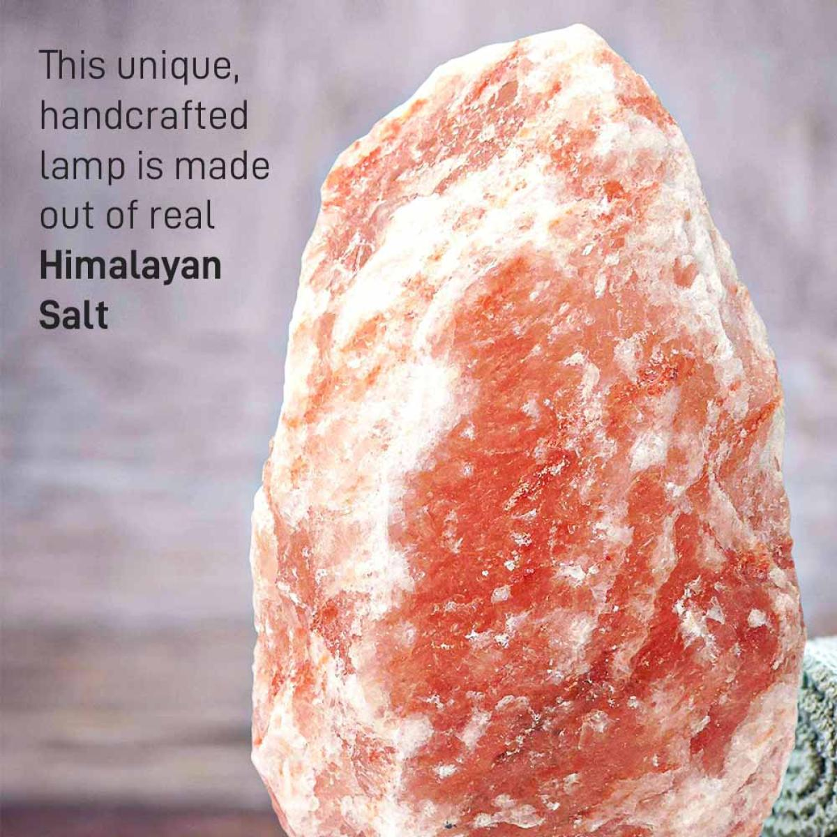 Een close-up van een roze Himalaya zoutlamp. Het zout heeft een ruwe textuur en is gestreept met wit. Tekst links.
