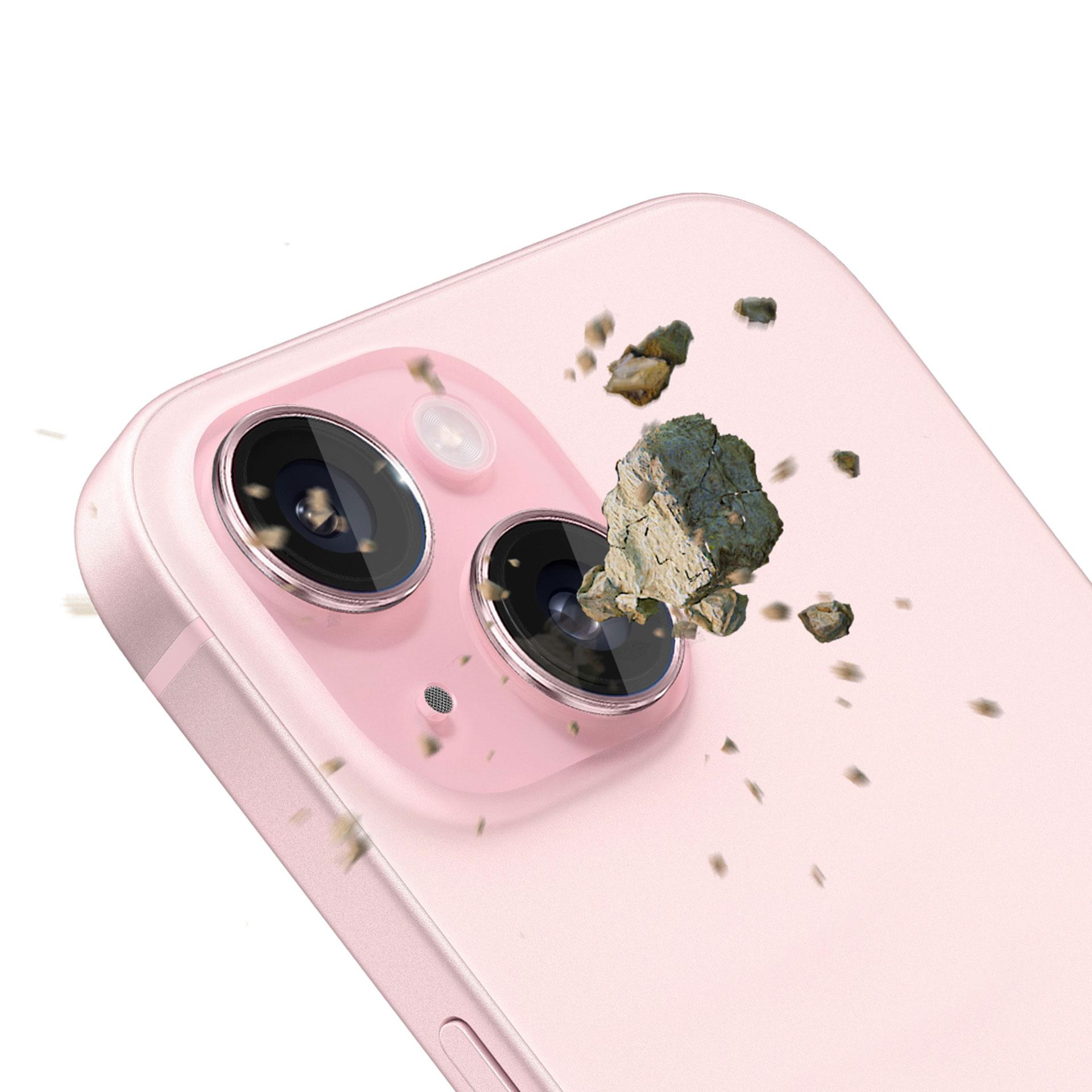 Telefono rosa con due obiettivi. Pezzi di roccia sembrano rompersi sugli obiettivi. Sfondo bianco.