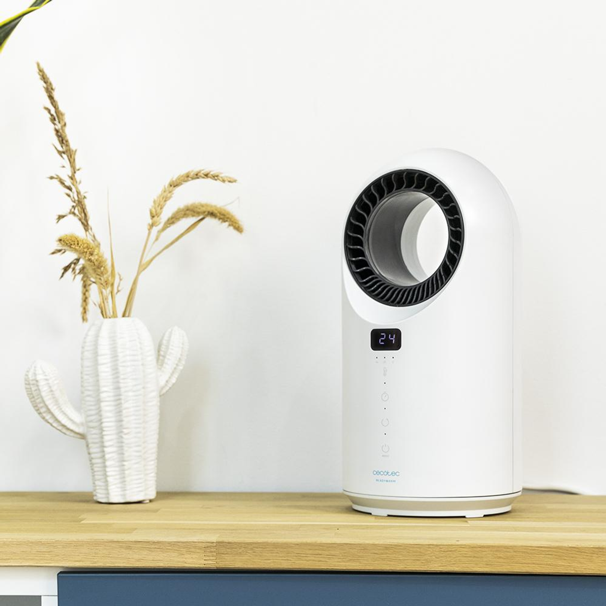 Biały oczyszczacz powietrza z cyfrowym wyświetlaczem 24, obok wazonu w kształcie kaktusa z suszonymi roślinami na drewnianej powierzchni.