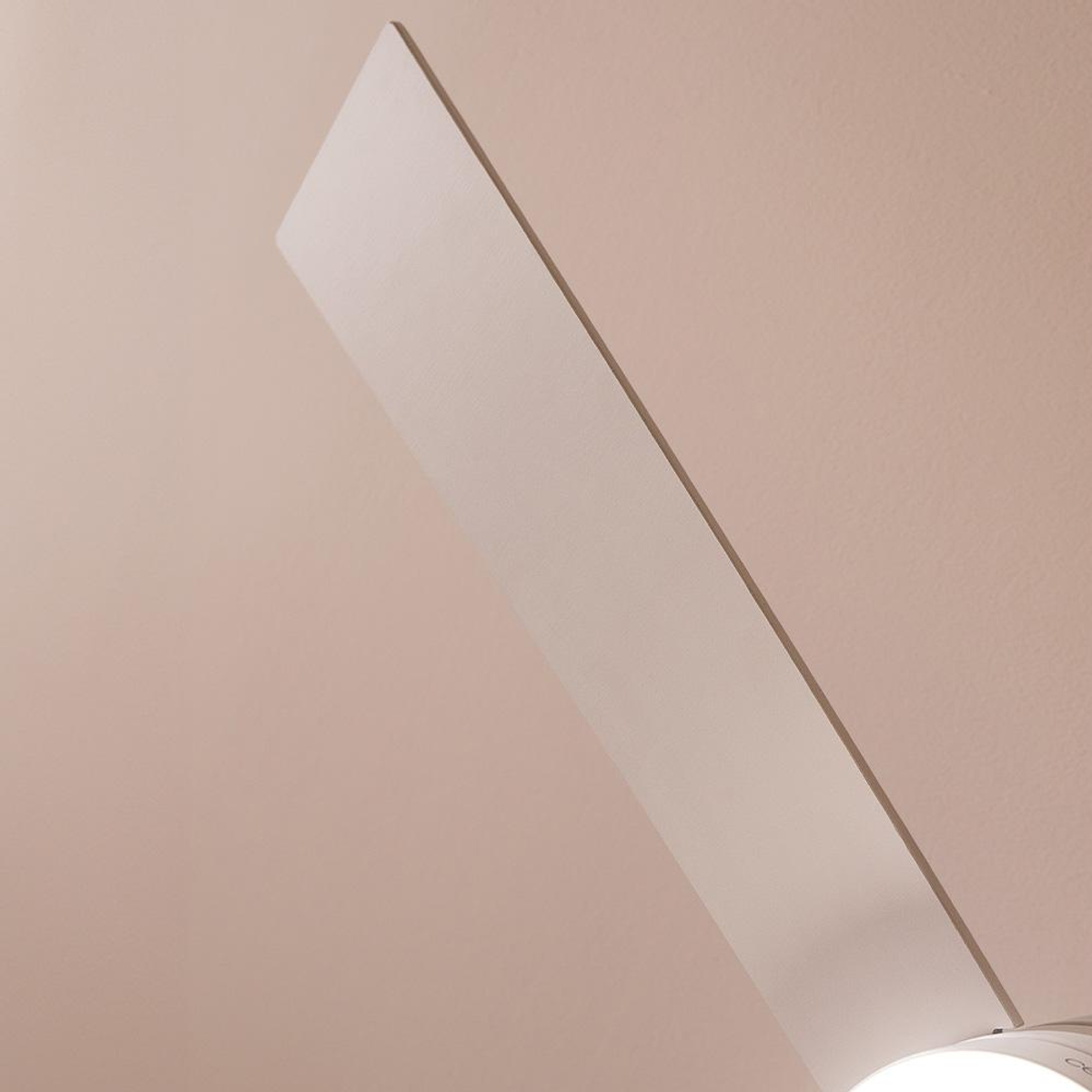 Zbliżenie łopatki wentylatora sufitowego na miękkim różowym tle. Łopatka jest biała i ustawiona pod kątem w kadrze.
