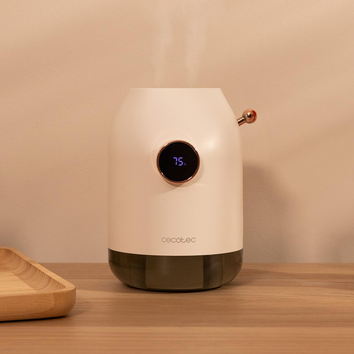 Ein weiß-grauer Luftbefeuchter auf einem Holztisch. Er hat eine Digitalanzeige mit 75 %. Links befindet sich ein Holztablett.