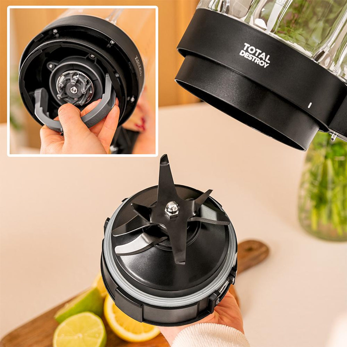 Nahaufnahme der Klingenanordnung eines Mixers, Teile des Mixers. Eine Hand hält die Klinge. Auf einem Holzbrett liegen geschnittene Zitronen und Limetten.