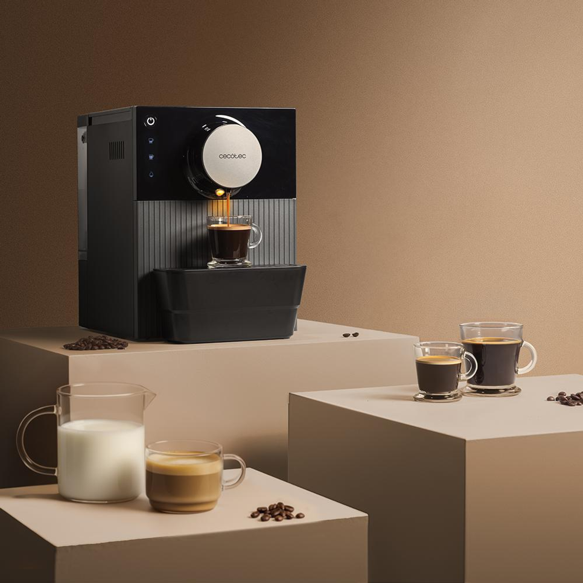 Macchina del caffè che eroga caffè in una tazza di vetro. Caffè, latte e chicchi di caffè su superficie marrone.