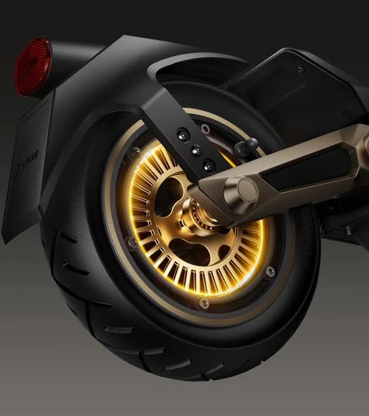 Primo piano di una ruota di scooter elettrico nera e dorata. La ruota ha un mozzo dorato, uno pneumatico nero e una luce rossa.