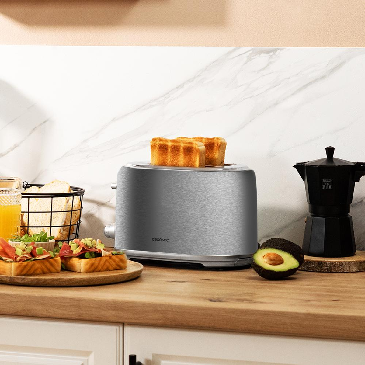 Scena kuchenna z tosterem, tostami, ekspresem do kawy i awokado na drewnianym blacie. Tosty są złote.