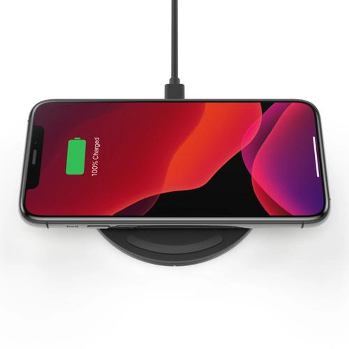 Ein Smartphone auf einem kabellosen Ladegerät. Der Bildschirm zeigt einen roten und violetten Hintergrund mit 100% Ladestatus.