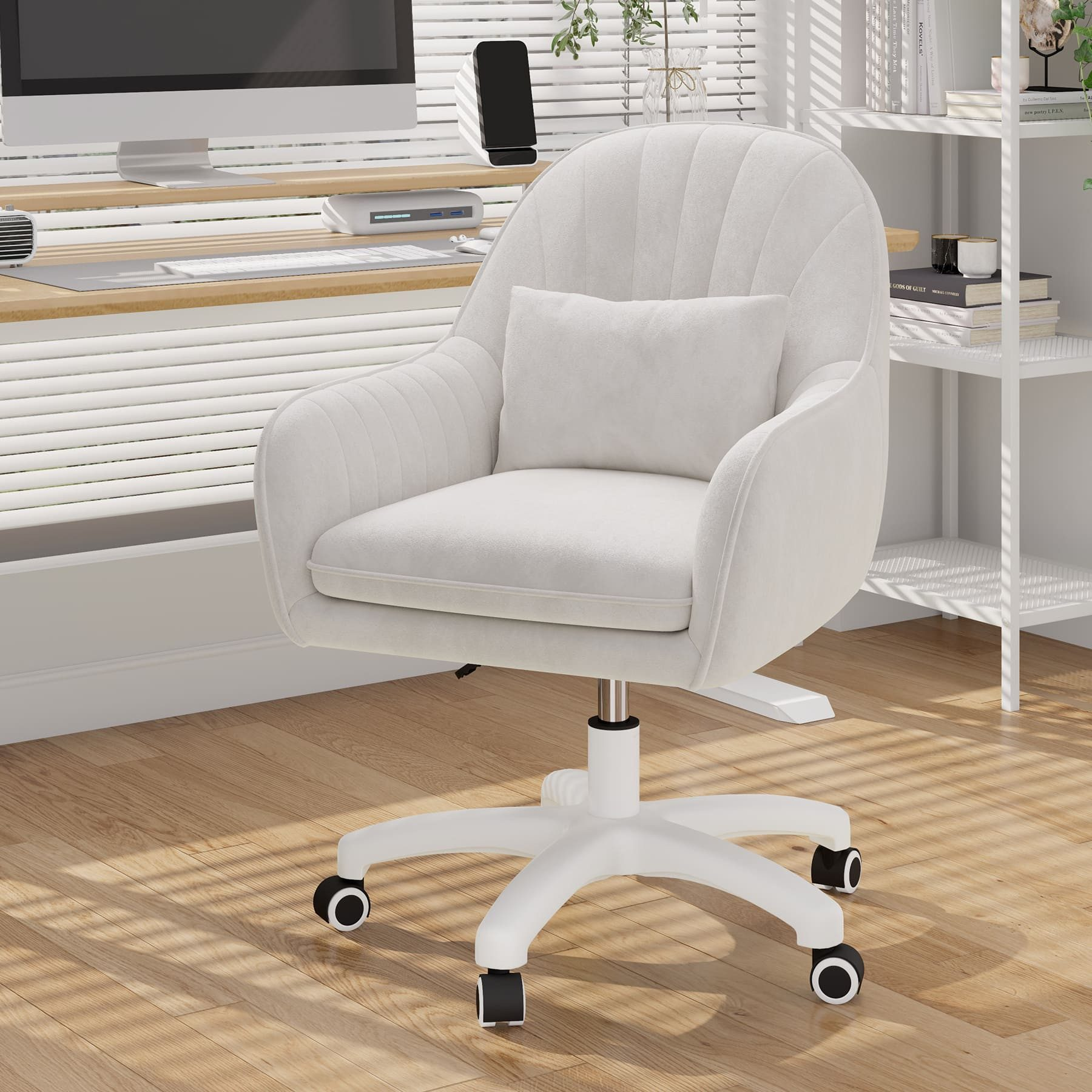 Una silla de oficina blanca con ruedas está frente a un escritorio. Una computadora y accesorios están en el escritorio.