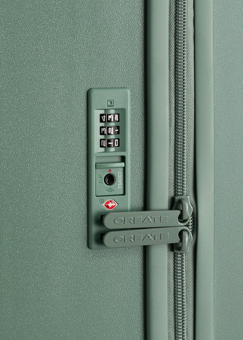 Primer plano de un candado verde de maleta con combinación 4320. Debajo, dos cierres CREATE son visibles, con la cremallera a la derecha.