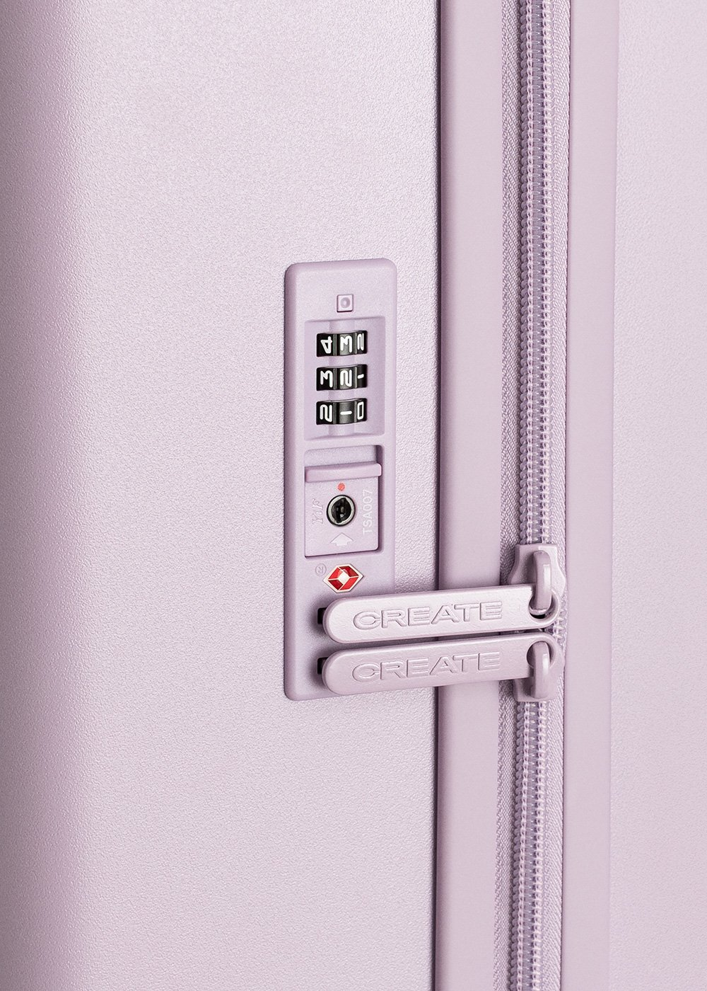 Primer plano de una cerradura de maleta lavanda con dial de combinación, cerradura TSA y cremallera. La palabra 'CREATE' es visible.