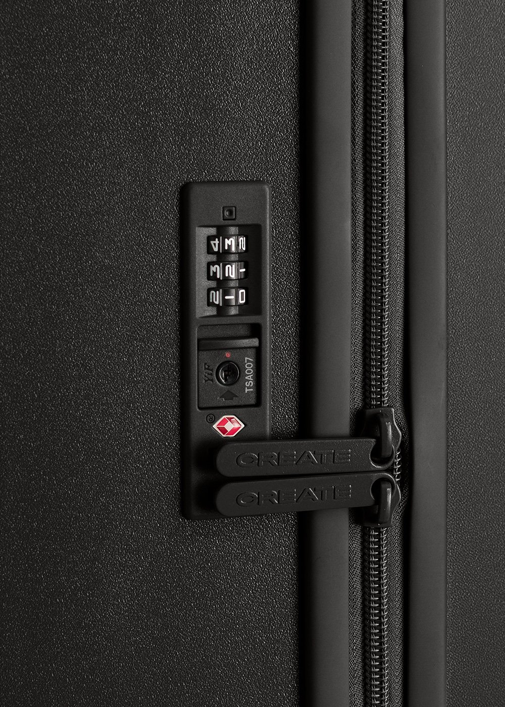 Primer plano de un candado de maleta negro con dial de combinación, cremallera y logotipos CREATE. Marca TSA007 visible.