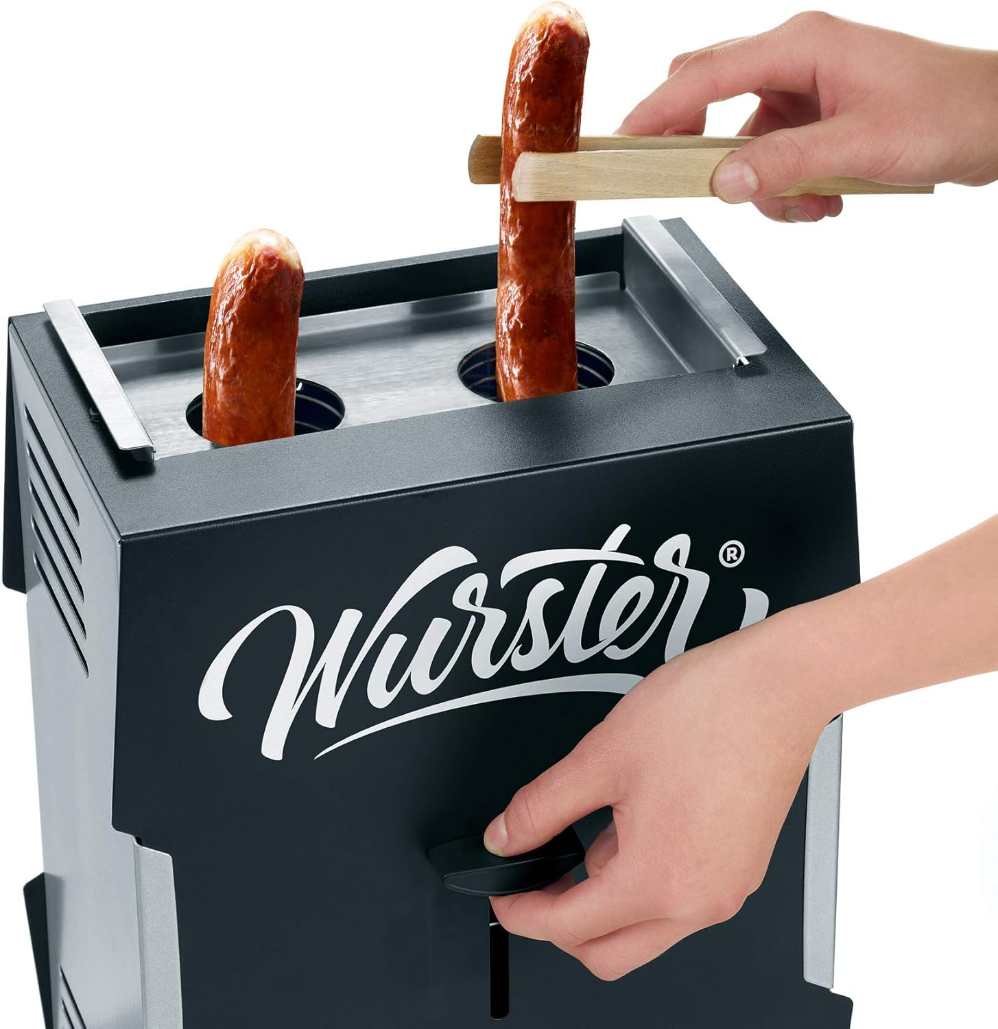 Ein Würstchenwärmer mit zwei Würstchen. Hände benutzen Zange und Hebel. Der Wärmer ist schwarz mit weißem 'Wurster' Logo.