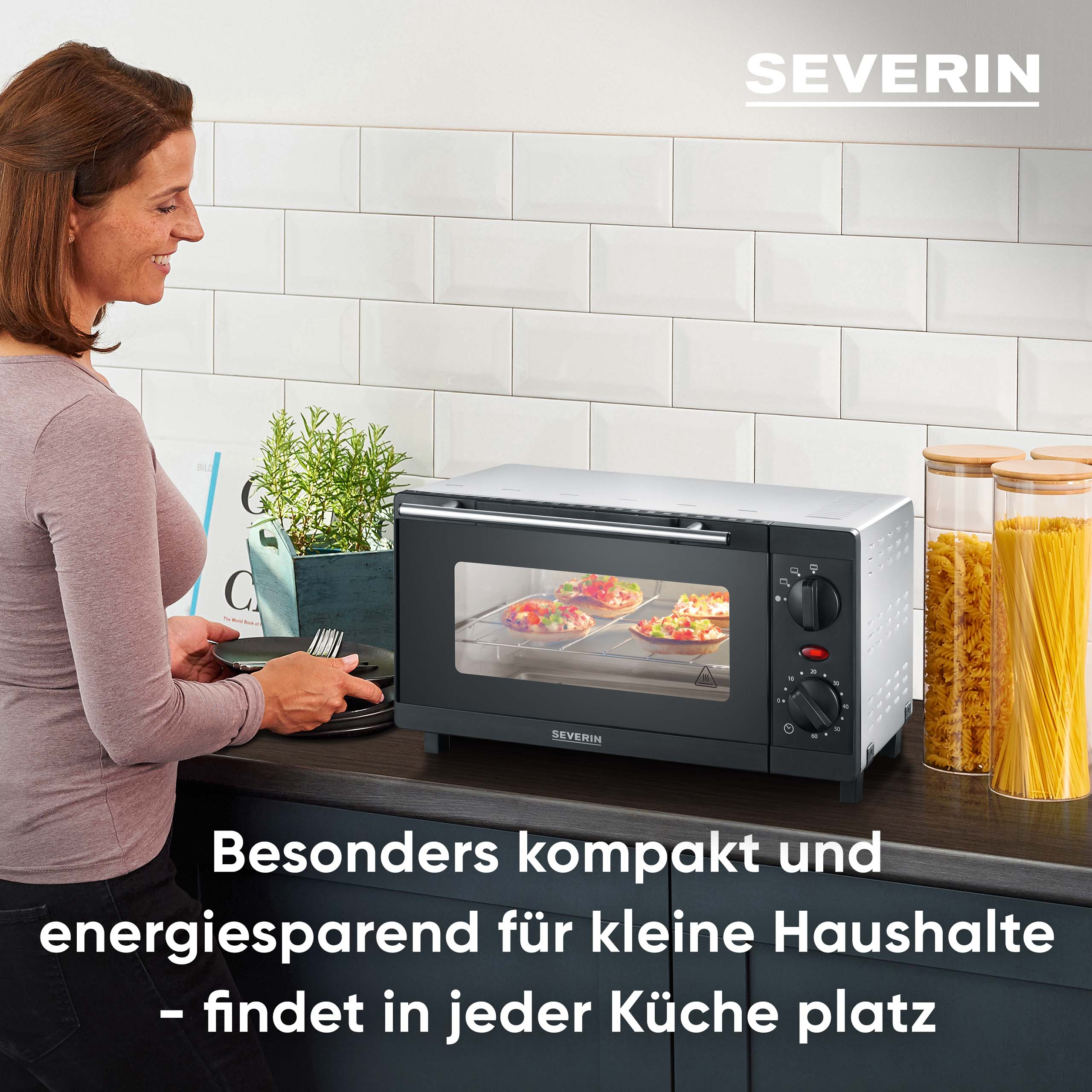 Kobieta stoi obok piekarnika SEVERIN z pizzą w środku. Słoiki makaronu na blacie.