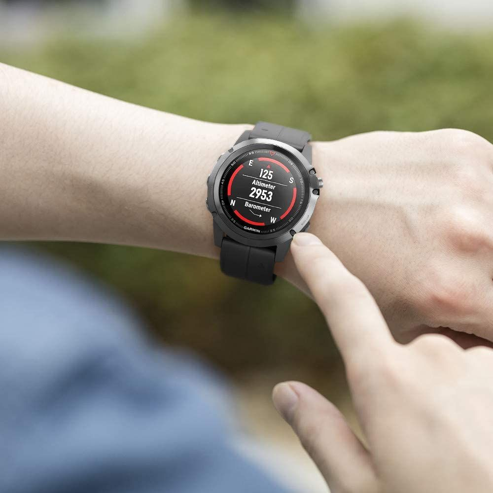 Eine Person trägt eine schwarze Smartwatch mit rundem Display, das Höhenmesseranzeigen zeigt. Die Person berührt die Uhr.