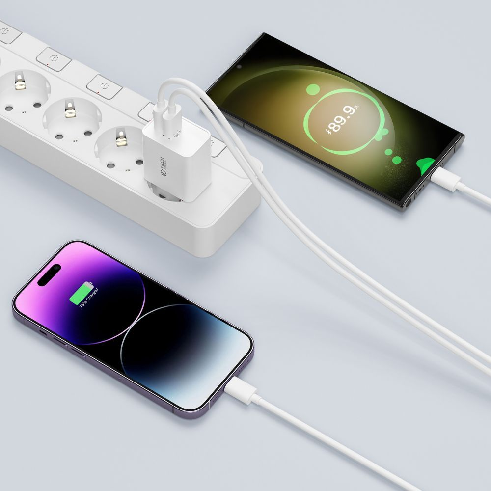Deux smartphones en charge, un à 75%, l'autre à 89,9%. Chargeur et câbles blancs connectés à une prise sur une surface bleu clair.