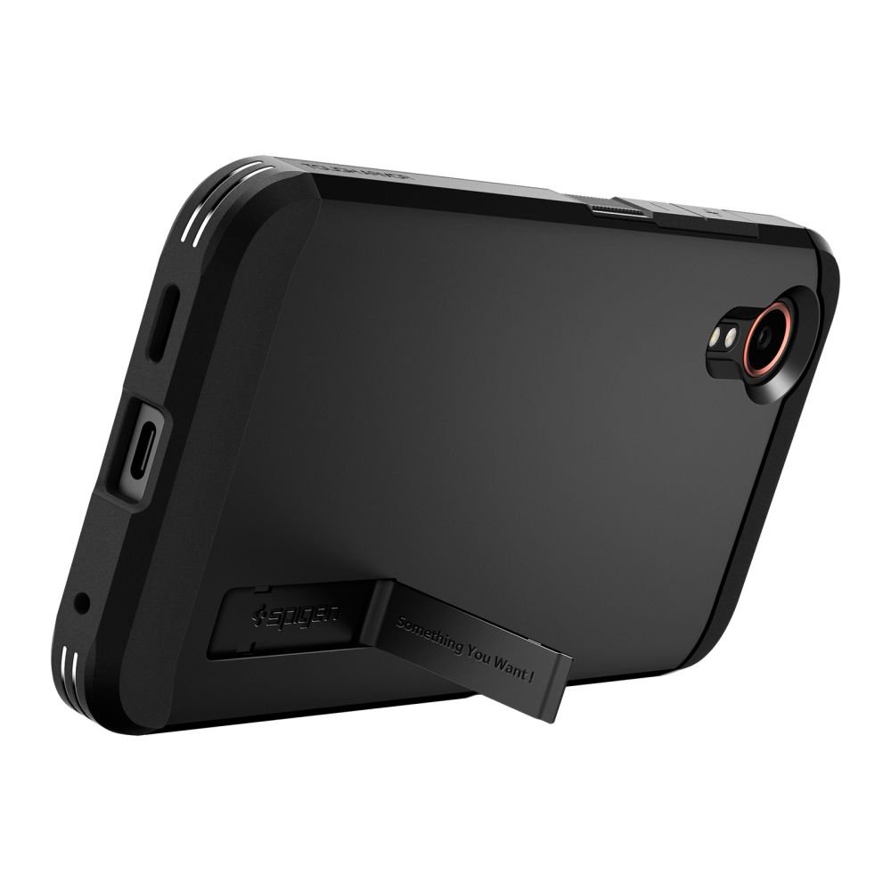 Coque de téléphone noire avec béquille. L'étui est incliné, montrant l'appareil photo et un logo Spigen. On peut lire : 'Something You Want!'