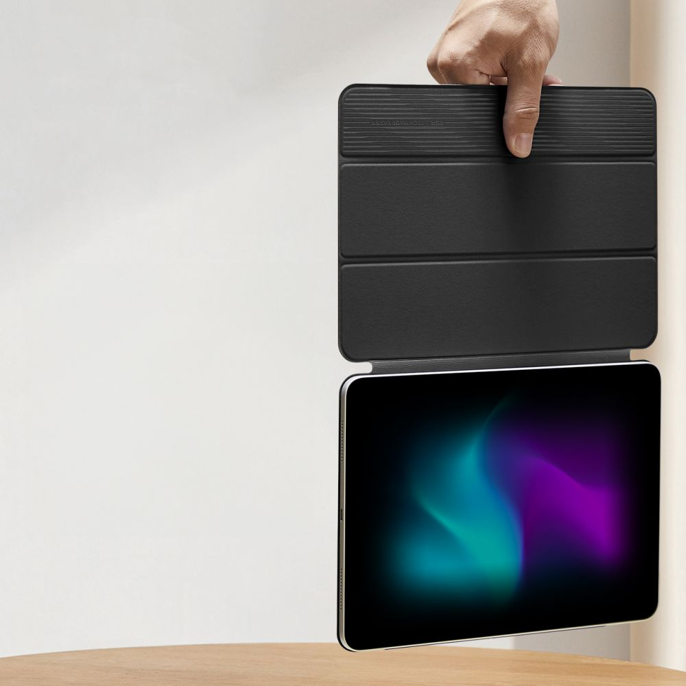 Eine Hand hält ein schwarzes Tablet mit schwarzer Hülle. Der Bildschirm zeigt einen Farbverlauf aus Blau, Grün und Lila.