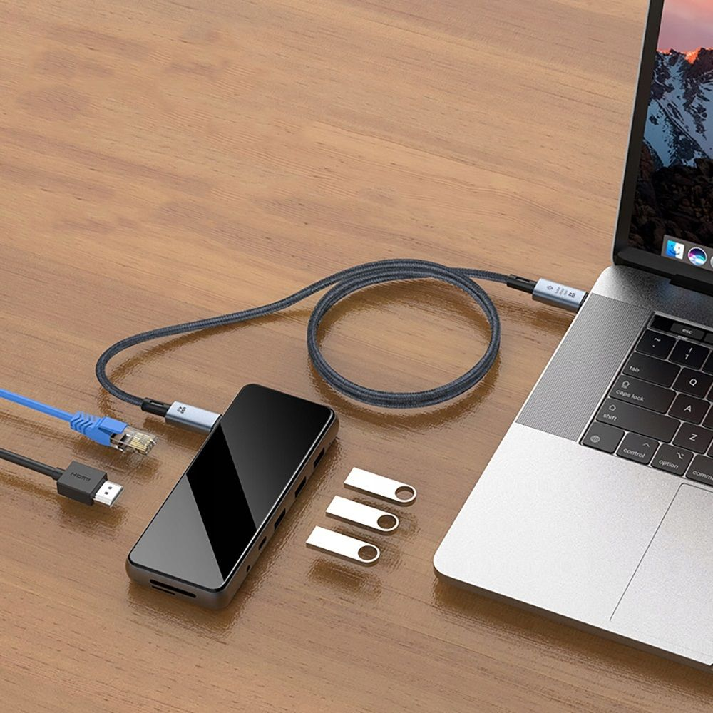 Un ordinateur portable connecté à un hub avec des câbles, des lecteurs USB sur une table en bois. Les câbles sont bleus, noirs et gris.