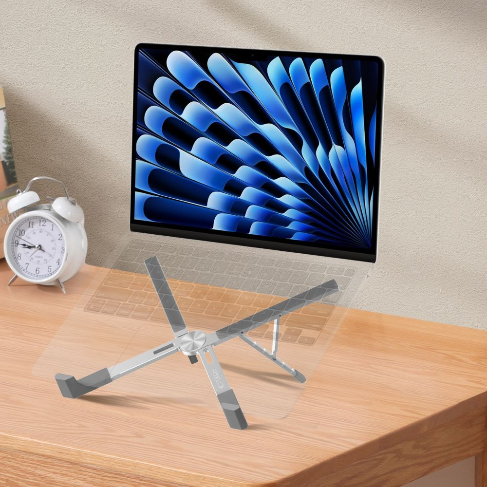 Laptop on a stand, white clock, and wooden desk. The laptop screen displays a blue abstract design.