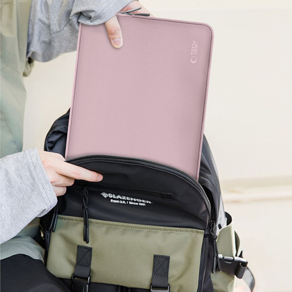 Een persoon die een roze laptoptas in een zwarte en groene rugzak plaatst. De tas heeft een tech-logo.